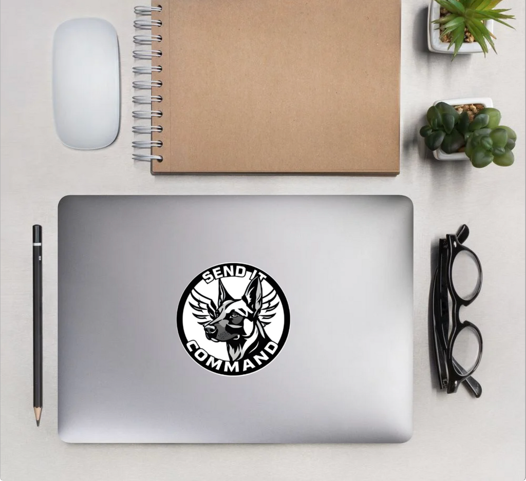 Stylish SEND IT COMMANDO sticker on a laptop, showcasing durability and bold design in a workspace setting.